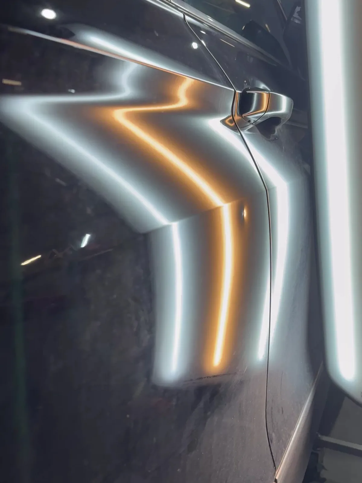 Reflexionsband der PDR-Lampe auf einer dunklen Fahrzeugtür macht die Delle sichtbar